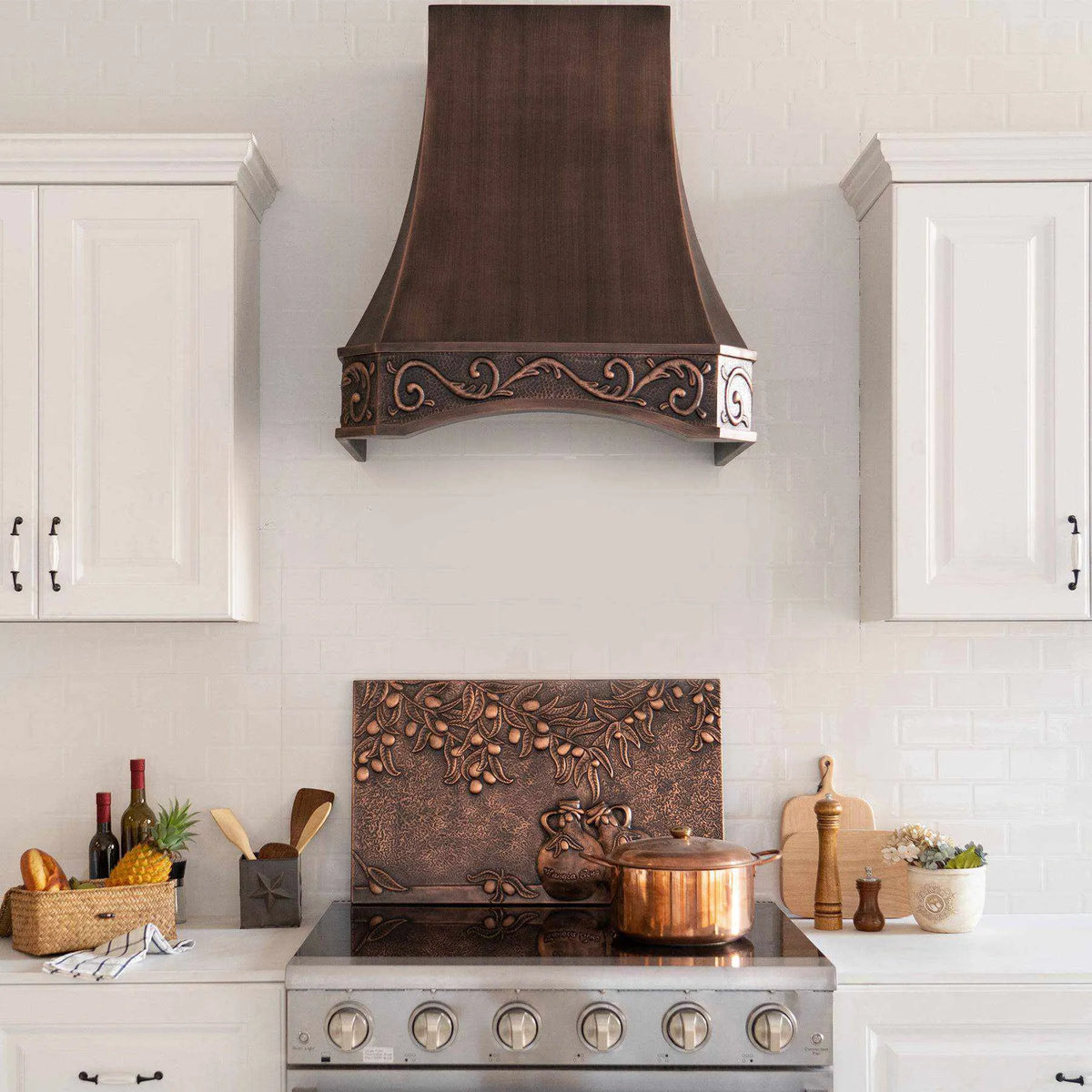 Antique copper range hood with intricate design, installed above a kitchen stove, with vintage apron pattern.