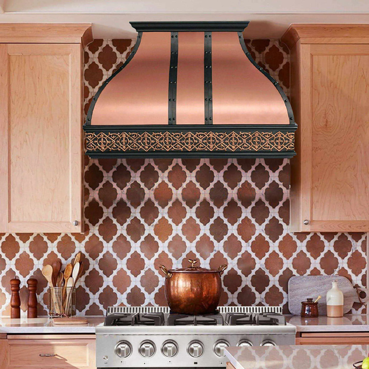 A natural copper range hood with black straps installed above a kitchen stove, featuring an antique classic pattern.