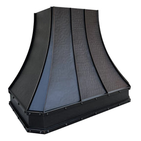 A bronze copper range hood with rivet details, displayed in a kitchen setting above a cooking area.
