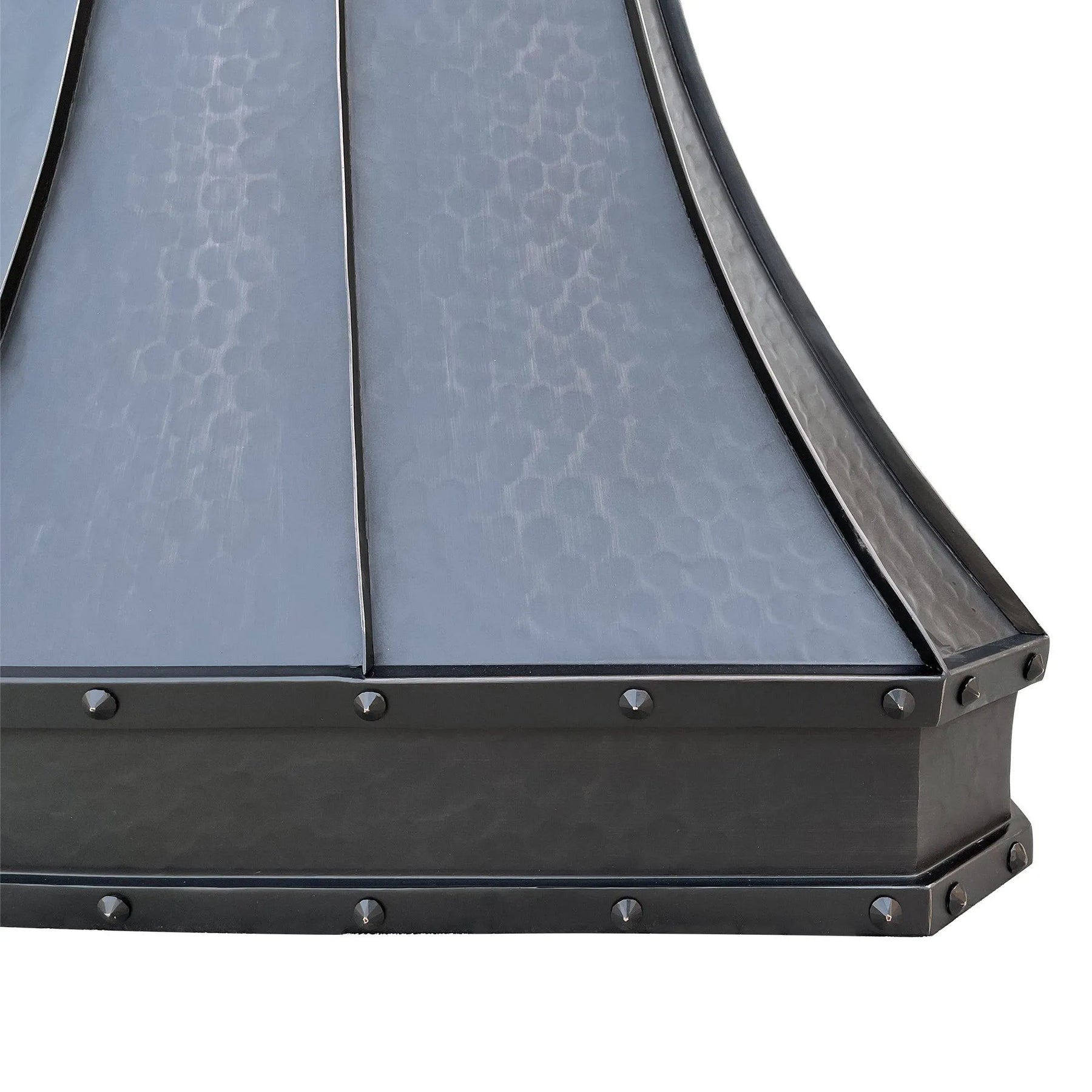 A bronze copper range hood with rivet details, displayed in a kitchen setting above a cooking area.