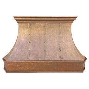 A handmade vintage copper range hood installed above a kitchen stovetop, featuring a curved design with rivets and straps.