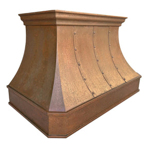 A handmade vintage copper range hood installed above a kitchen stovetop, featuring a curved design with rivets and straps.