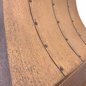 A handmade vintage copper range hood installed featuring natural oxidized texture