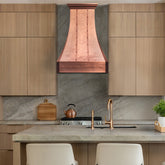 Modern kitchen with wooden cabinets, copper range hood, and marble countertop.