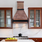 Kitchen with copper range hood, wooden cabinets, and a stove.